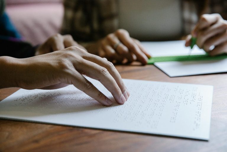 Manos escribiendo en hojas de papel sobre una mesa de madera.